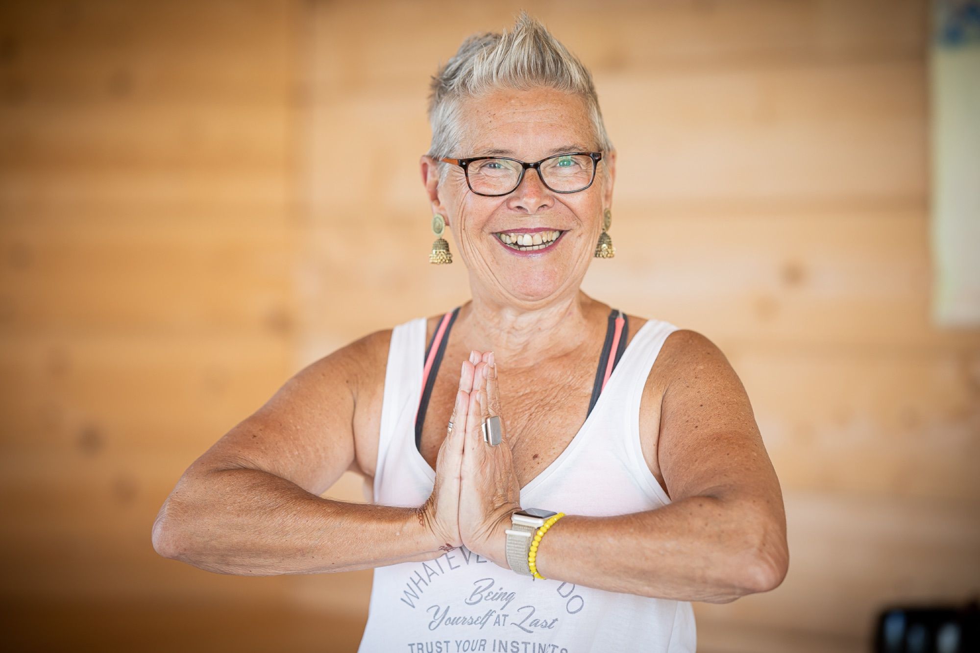Yogadocent glimlacht met de handen gevouwen voor het hart