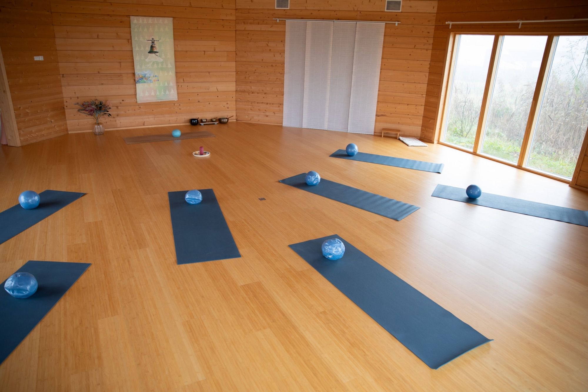 De houten, achthoekige zaal met yogamatten en uitzicht op het groen